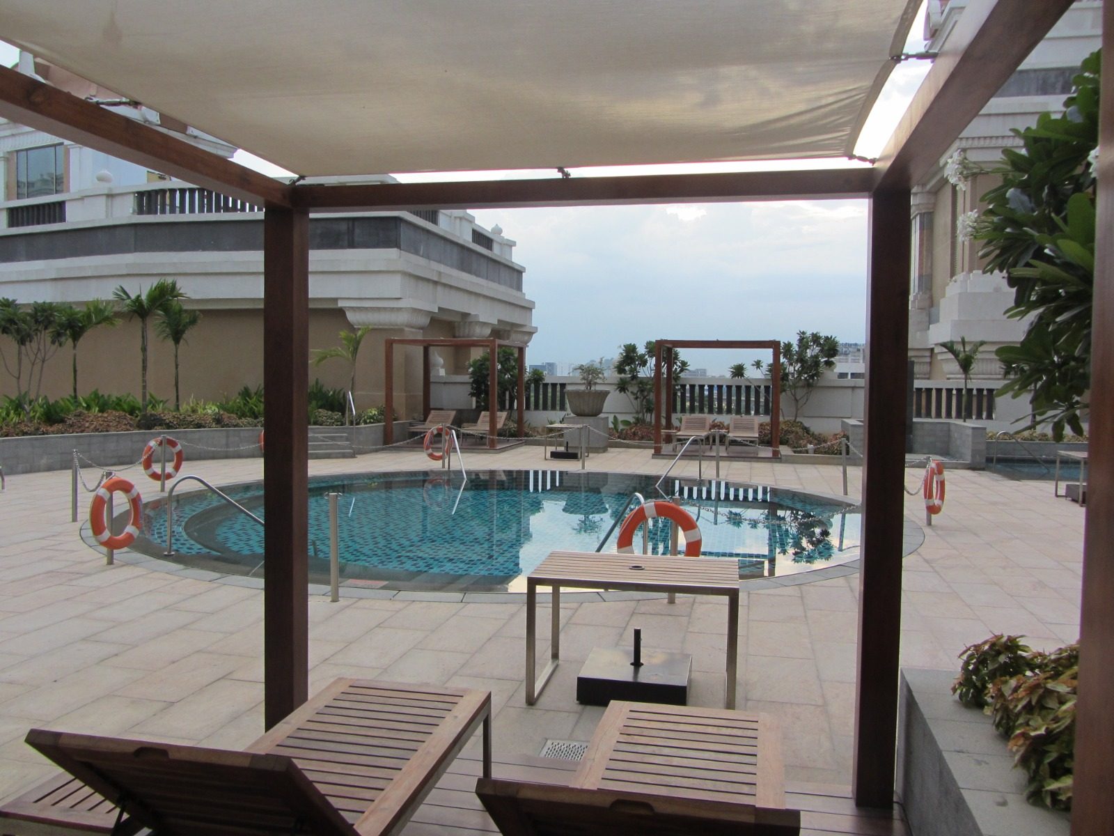 Shaded poolside deck at ITC with timber pergolas, loungers and planting above the city