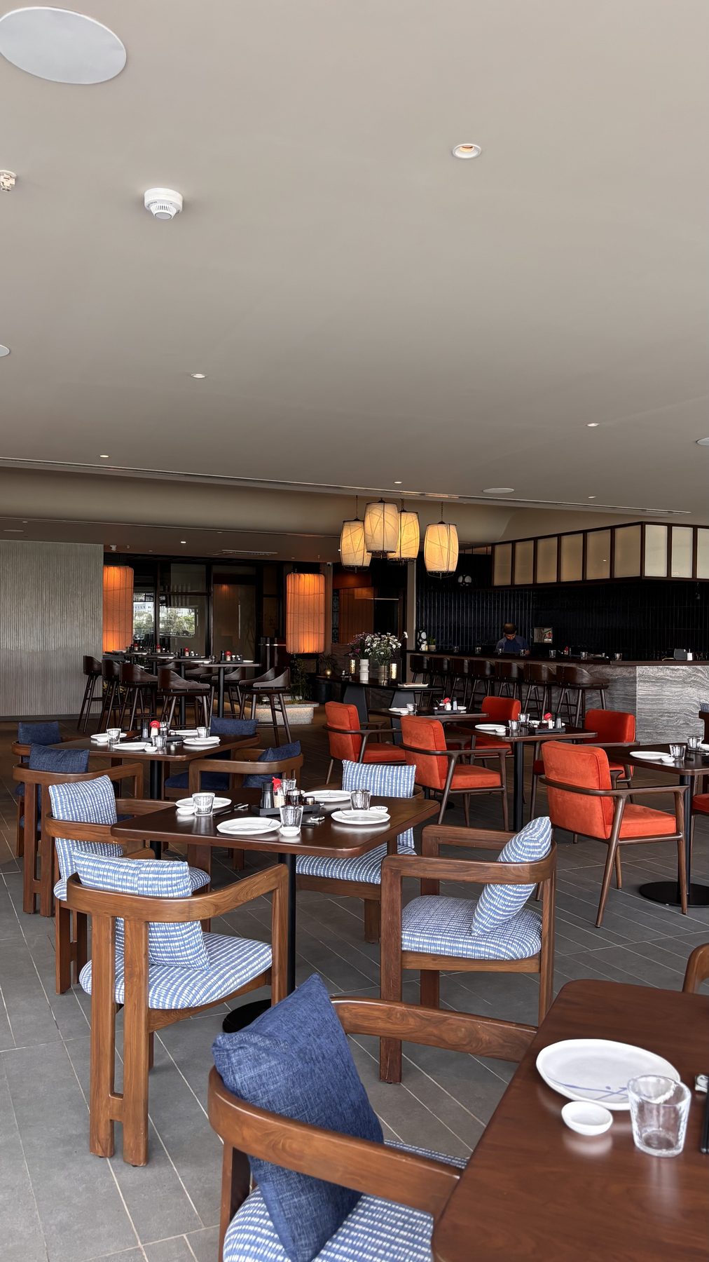 Izumi dining room with paper lanterns, walnut tables and indigo and vermilion seating