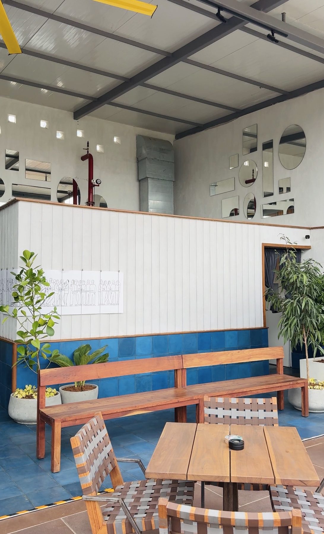 Open-air seating with cobalt tiling, teak benches and a scattered cluster of mirrors