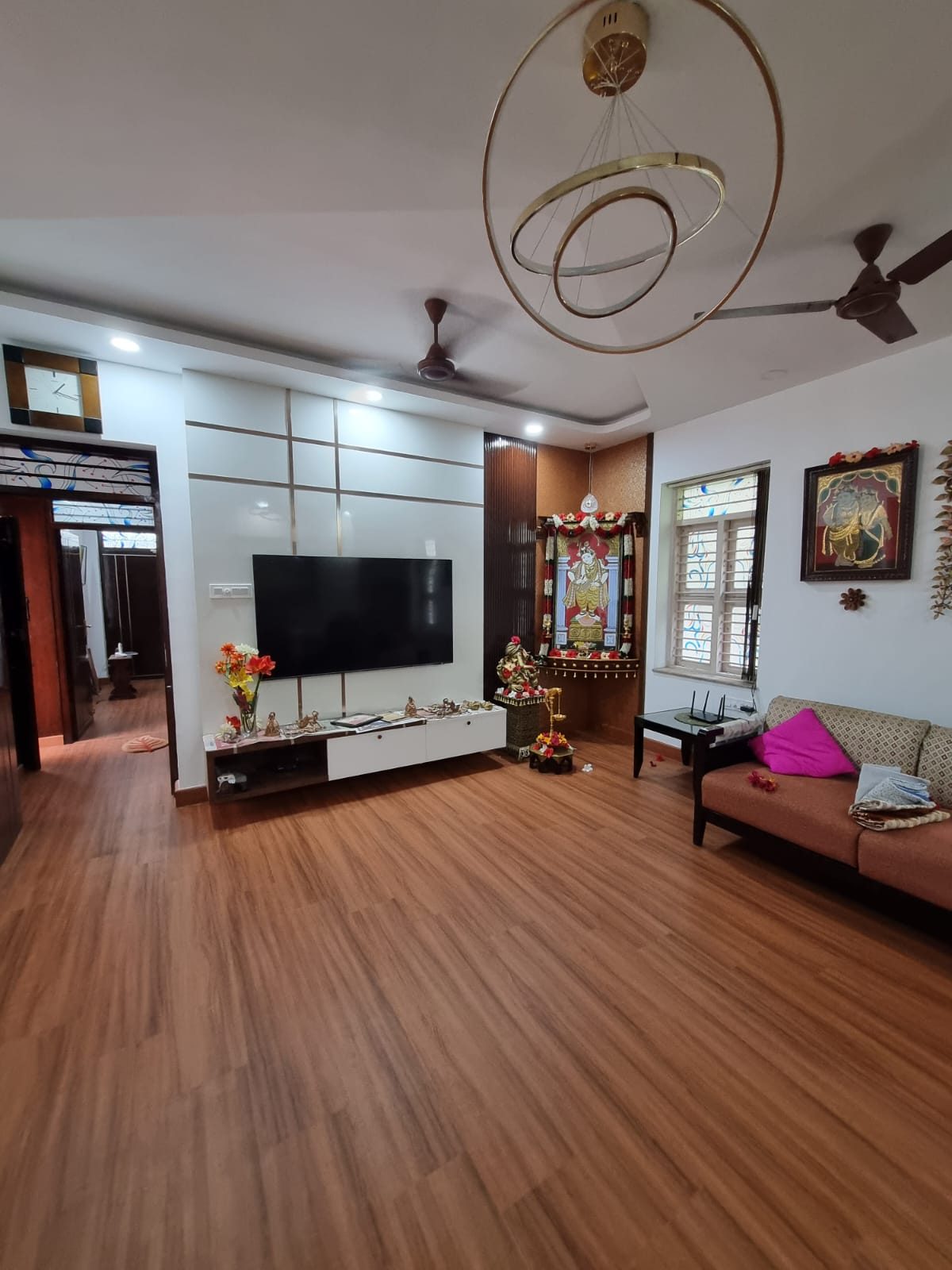 Family living room with a fluted timber pooja niche, media wall and warm oak flooring