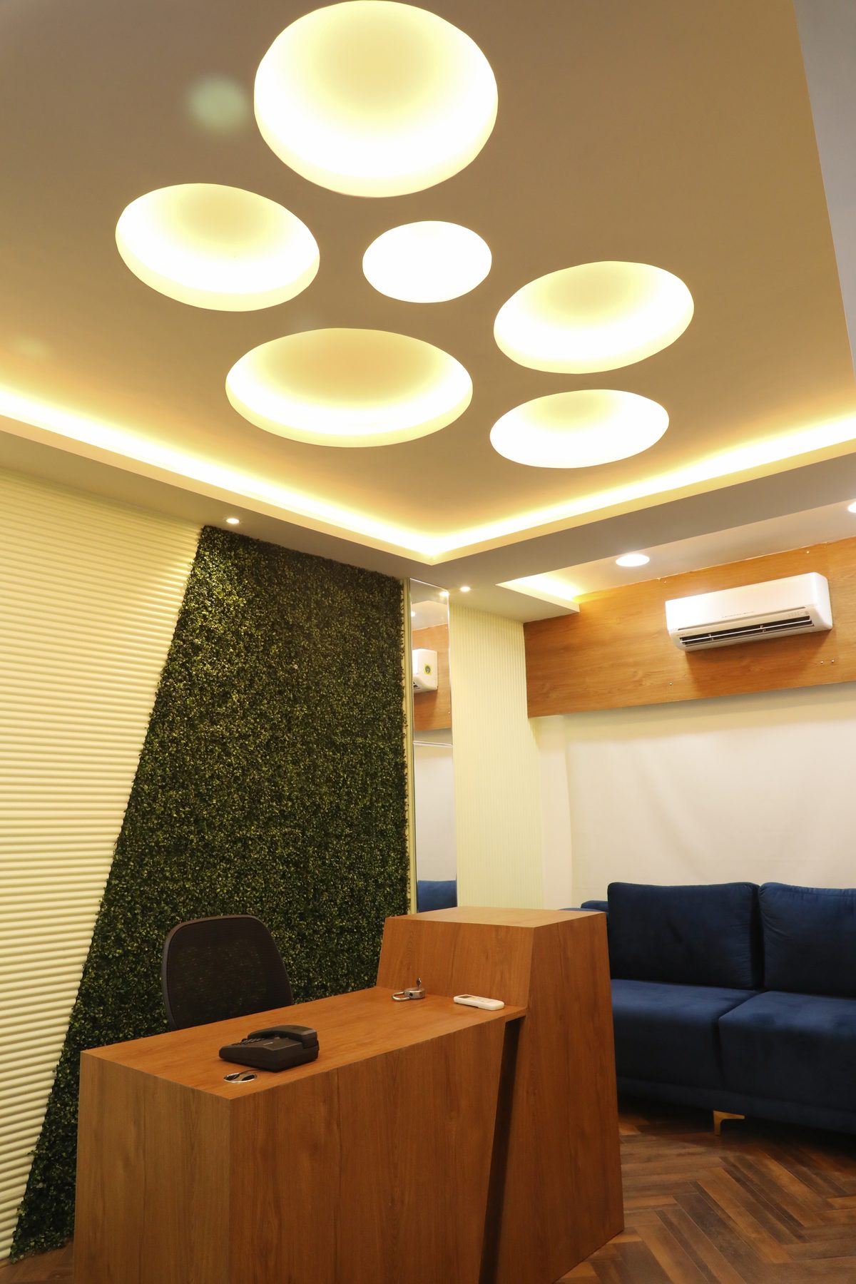 Reception with a preserved moss wall, timber desk and a ceiling of backlit discs